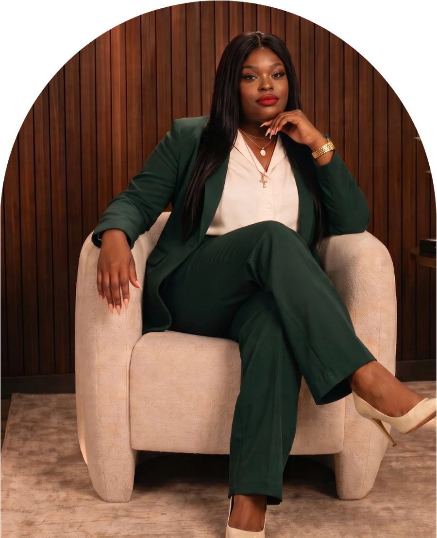 Tiffany Elle seated in an armchair in a dark green suit